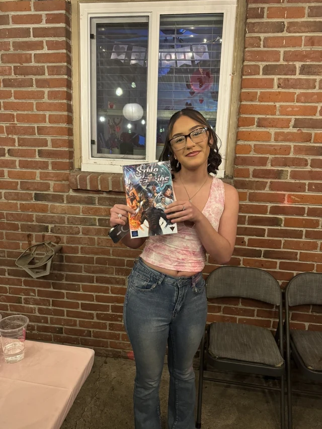 Reader holding the Style Assassins standard-cover comic in front of a brick wall.